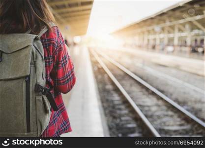 Young Asian woman backpacker traveler walking alone at train station platform with backpack. Asian woman waiting train at train station for travel. Summer holiday traveling or young tourist concept.