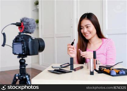 Young asian woman beauty blogger showing cosmetic while recording how to make up video tutorial by camera, vlog concept, beauty and fashion people and technology communication