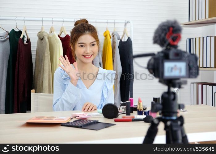 Young asian woman beauty blogger showing how to make up video tutorial recording by camera, vlog concept, fashion people and technology communication