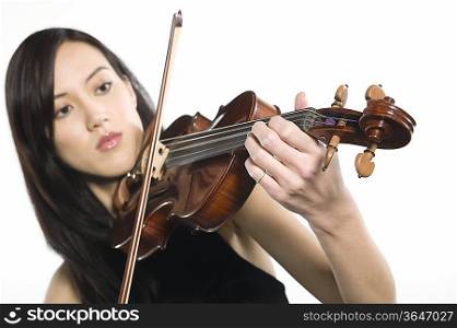 Young Asian woman concentrates on playing the violin