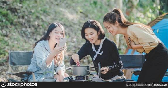 Young asian woman cooking and her friend enjoy to make the meal in pot, They are talk and laugh with fun together while c&ing in nature park