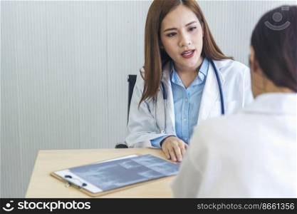 Young asian woman doctor meeting at office table. Two women doctors discussing diagnosis meeting in hospital office medical clinic looking x-ray film consulting patient disease medical lab discussion