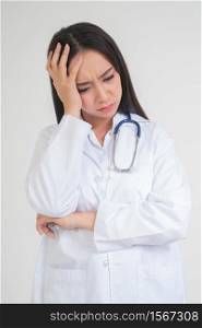 Young Asian woman doctor standing and holding hands in the head Due to headache, she looks unhappy and tired because of overwork, Concept of stressed and doctor liability, Dealing with frustrated