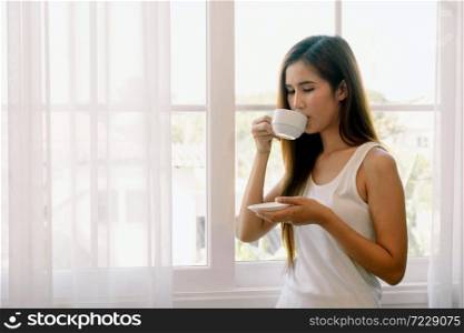 Young asian woman drinking coffee. She stay isolation at home for self quarantine. Corona virus outbreak situation. Self quarantine at home prevention COVID-19.