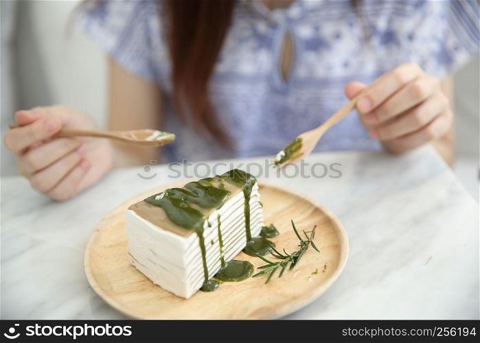 Young Asian Woman eating Green tea crape cake sweet food