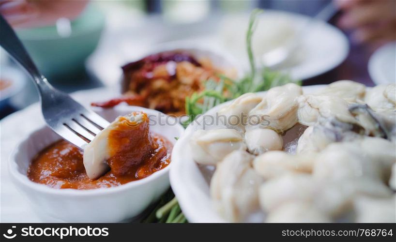 Young Asian woman eating oyster seafood in restaurant, teenager female feeling happy eating food. Women eating seafood concept.