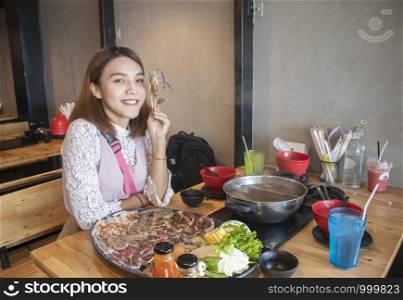 young asian woman enjoy eating Shabu-Shabu japanese hot pot
