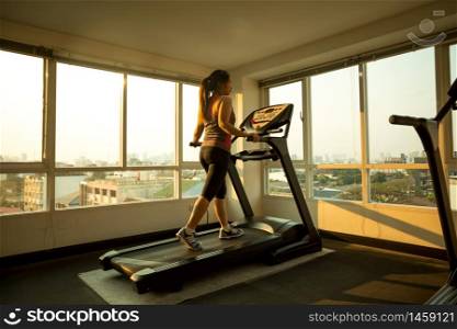 Young asian woman exercising on a treadmill
