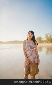 Young Asian woman feeling happy on beach, beautiful female happy relax smiling fun on beach near sea when sunset in evening. Lifestyle women travel on beach concept.