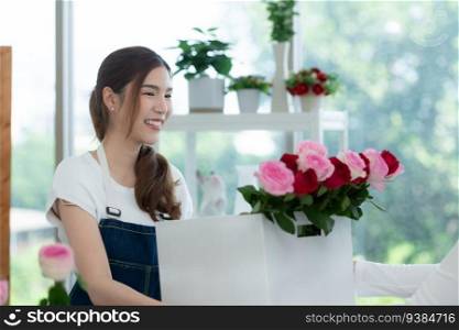 Young asian woman florist working at flower shop, she is happy and smiling. deliver flowers to customers