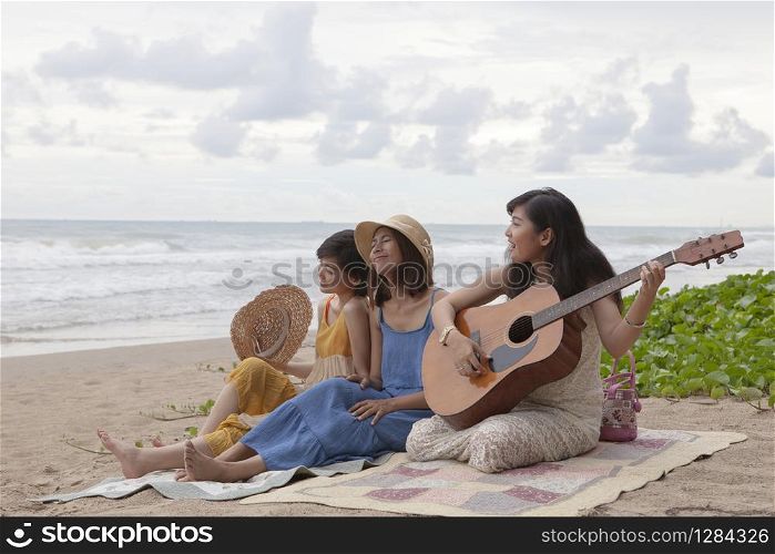 young asian woman friend playing guitar on sea beach happiness emotion on summer vacation
