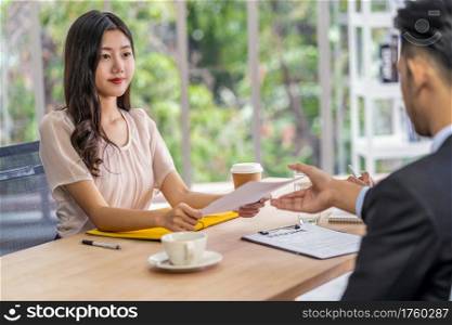 Young Asian woman graduate holding and Submitting the resume document to two manager before start to job interview with positive motion in meeting room,Business Hiring new member concept