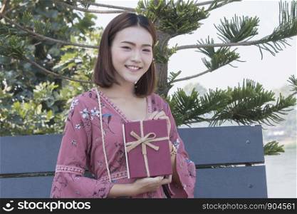 Young asian woman happy smile hold gift box in hands at park
