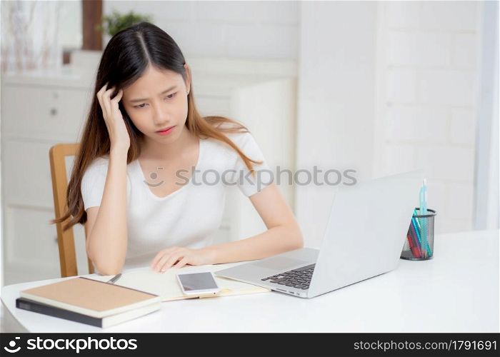 Young asian woman headache during working on laptop computer with deadline on desk at home, business woman with failure exhausted and tired, stress and worried, frustrated and unsuccessful.