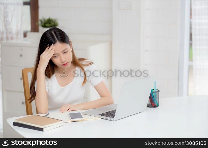 Young asian woman headache during working on laptop computer with deadline on desk at home, business woman with failure exhausted and tired, stress and worried, frustrated and unsuccessful.