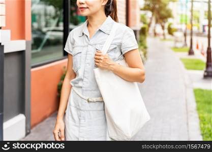 Young asian woman holding a reusable bag and walking in the city, Zero waste concept