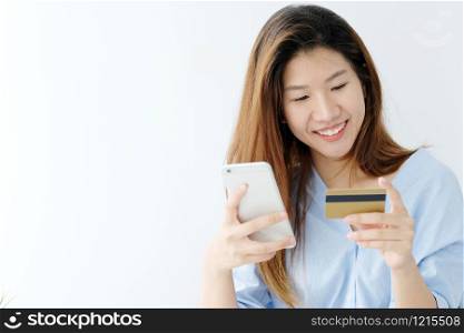 Young asian woman holding credit card and using smart phone for shopping online, business and technology concept, online payment, digital money