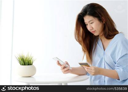 Young asian woman holding credit card and using smart phone for shopping online, business and technology concept, online payment, digital money
