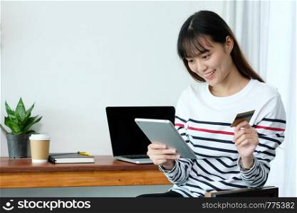 Young asian woman holding credit card and using tablet for shopping on line at cafe, business and technology concept, digital marketing, casual lifestyle