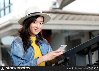 Young asian woman in casual style using smartphone while standing in the city outdoors background, people working outdoors with technology, urban lifestyle, people on phone
