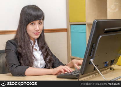 Young Asian Woman in Office Sitting at Desk
