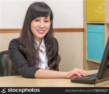 Young Asian Woman in Office Sitting at Desk