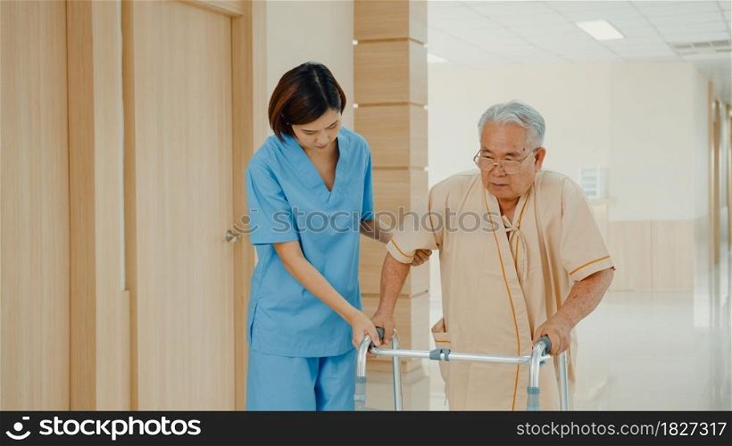 Young Asian woman nurse caregiver assistance encourage take care her senior patient explain with positive keep comforting for practice walker in hospital ward, Hospital environment concept.