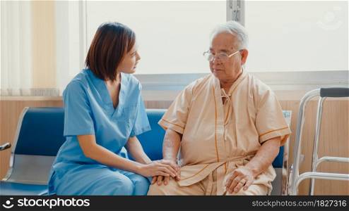 Young Asian woman nurse caregiver encourage take care her senior patient hold hand explain information use walker assistance in hospital ward, Epidemic and virus, Hospital environment concept.