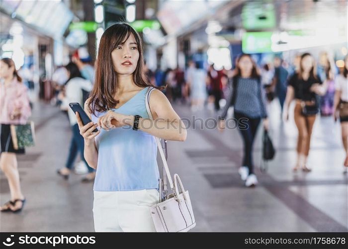 Young Asian woman passenger checking the time and waiting to her friend in subway train when traveling in big city,japanese,chinese,Korean lifestyle and daily life, commuter and transportation concept