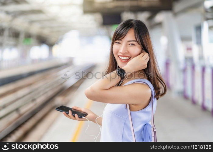 Young Asian woman passenger listening music via smart mobile phone in subway train when traveling in big city,japanese,chinese,Korean lifestyle and daily life, commuter and transportation concept