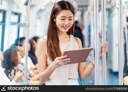 Young Asian woman passenger using mutimedia player via Technology tablet in subway train when traveling in big city,japanese,chinese,Korean lifestyle and daily life,commuter and transportation concept