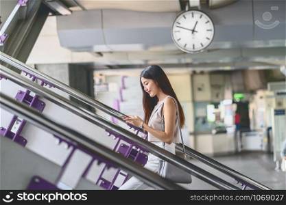 Young Asian woman passenger using smart mobile phone and walking up the stairs in subway station when traveling in big city,japanese,chinese,Korean lifestyle and daily life,commuter and transportation