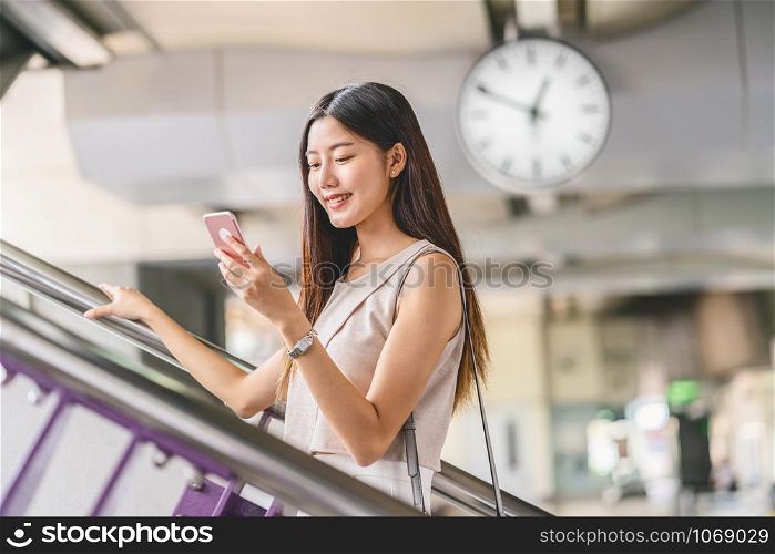 Young Asian woman passenger using smart mobile phone and walking up the stairs in subway station when traveling in big city,japanese,chinese,Korean lifestyle and daily life,commuter and transportation