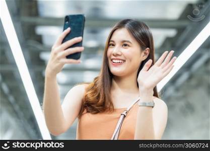 Young Asian woman passenger using smart mobile phone for selfie or video conference to her friend in subway interchange when traveling in big city,enjoy weekend vacation after covid19 Relaxation measures