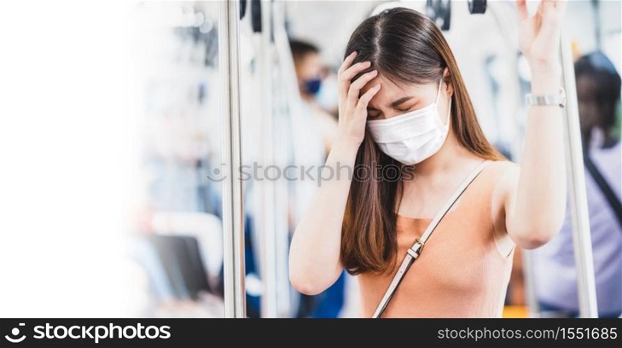Young Asian woman passenger wearing surgical mask and Having a headache in subway train when traveling in big city at Covid19 outbreak, Infection and Pandemic,new normal and illness prevention concept