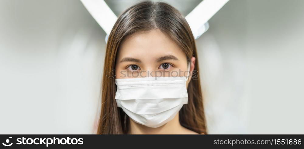 Young Asian woman passenger wearing surgical mask and looking at camera in subway train when traveling in big city at Covid19 outbreak, Infection and Pandemic, social distancing and new normal concept