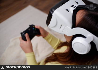 Young asian woman playing video games wearing virtual reality glasses inthe living room