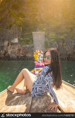 Young asian woman relax on long tail boat at Maya bay, Phi Phi island , Phuket in Thailand