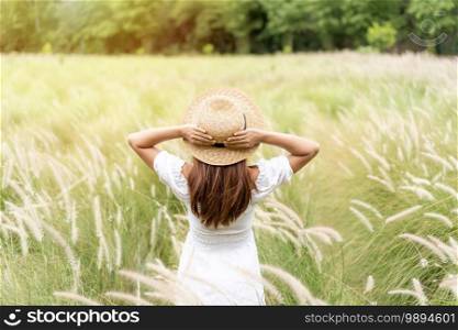 Young asian woman relaxing and enjoying in the flower field while traveling in summer