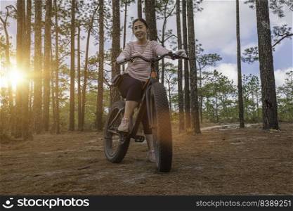Young asian woman riding bicycle in pine forest.