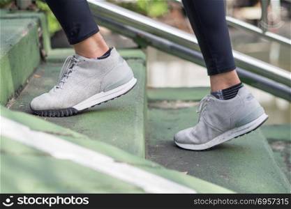 Young asian woman running on sidewalk in morning. Health conscio. Young asian woman running on sidewalk in morning. Health conscious concept with copy space. Young sport asian woman running upstairs on city stairs. Fitness sport people and healthy lifestyle concept.