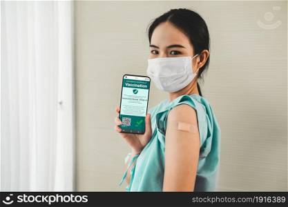 Young Asian woman shows vaccine passport on mobile phone to validate travel permission by the digital document. Vaccine Passport V2