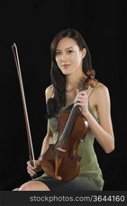 Young Asian woman sits holding a violin