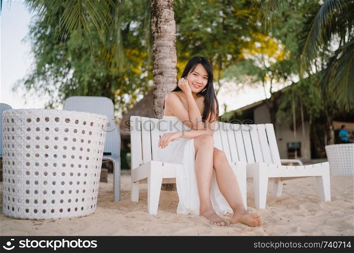 Young Asian woman sitting on bench relax on beach, Beautiful female happy relax near sea. Lifestyle women travel on beach concept.