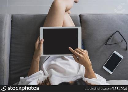 Young asian woman sitting on sofa and using tablet at home. Young asian woman using tablet at home