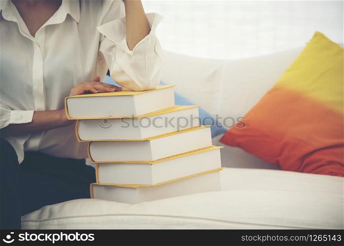 Young Asian Woman student university holding text book on her hands sitting on sofa with colorful pillow. Study hard to get a better grade. Education Concept