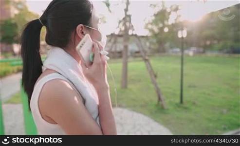 Young asian woman take off protective face mask, get ready before exercise, sunset light on background, holding cellphone, stay healthy during pandemic covid19 corona virus, distancing work out