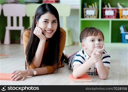 Young asian woman teacher and white boy in kindergarten classroom, preschool education concept