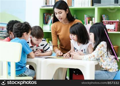 Young asian woman teacher teaching kids in kindergarten classroom, preschool education concept