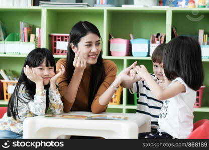 Young asian woman teacher teaching kids in kindergarten classroom, preschool education concept